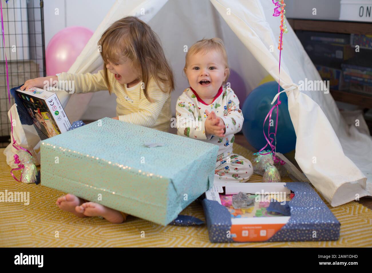 Geschwister sitzen in einem Tipi drinnen Eröffnung Geschenke, UK Stockfoto