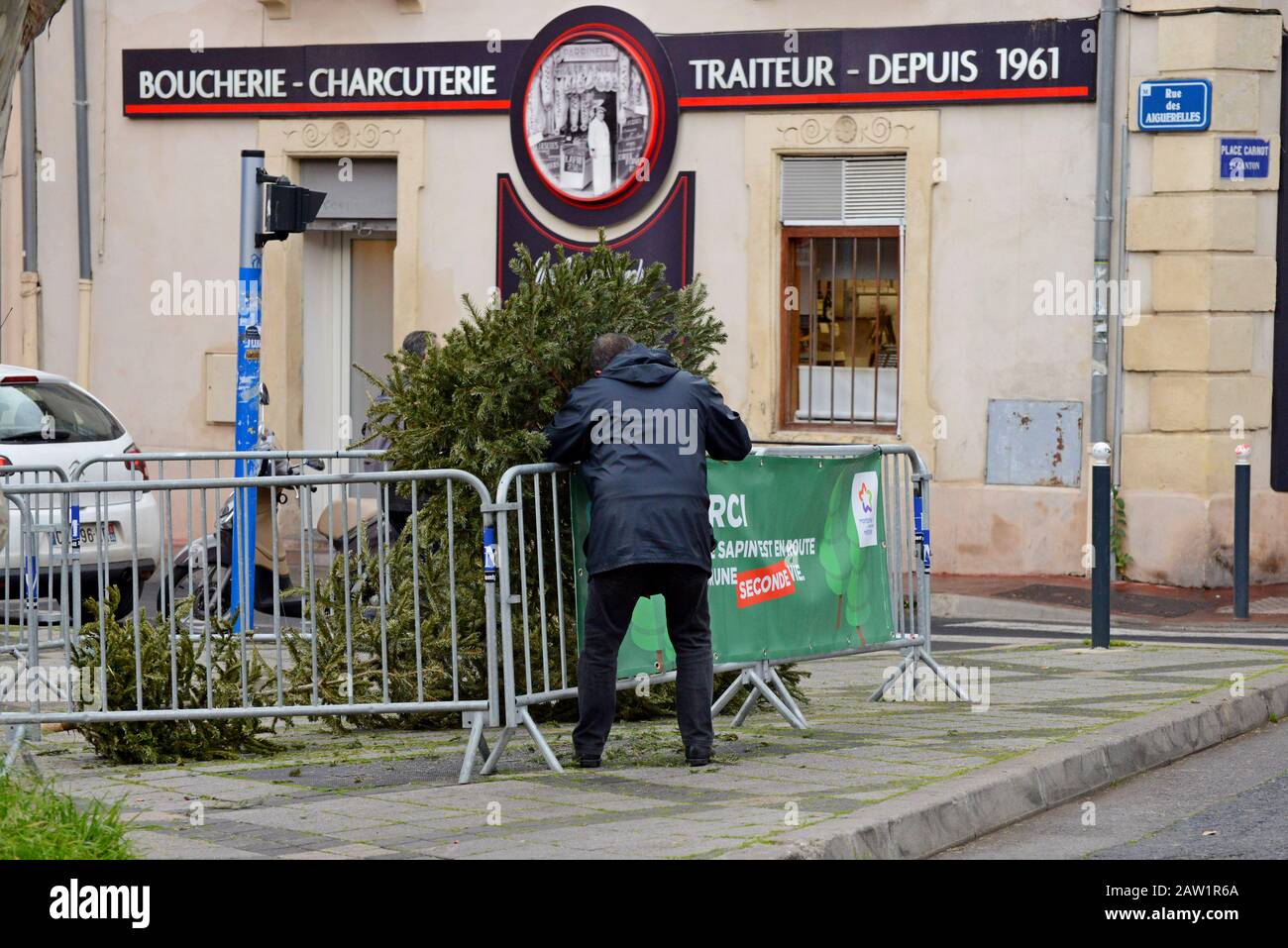 Ein Mann, der einen weihnachtsbaum an einer Recyclingstelle auf der Straße, Montpellier, Frankreich, recycelt Stockfoto