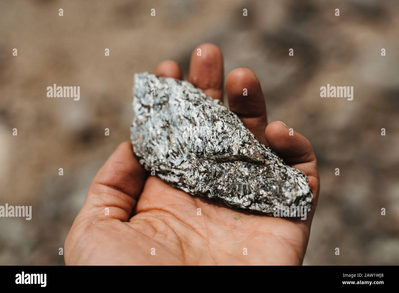 Hand mit silbernem zitternden Quarzstein in Der Mondlandschaft Stockfoto