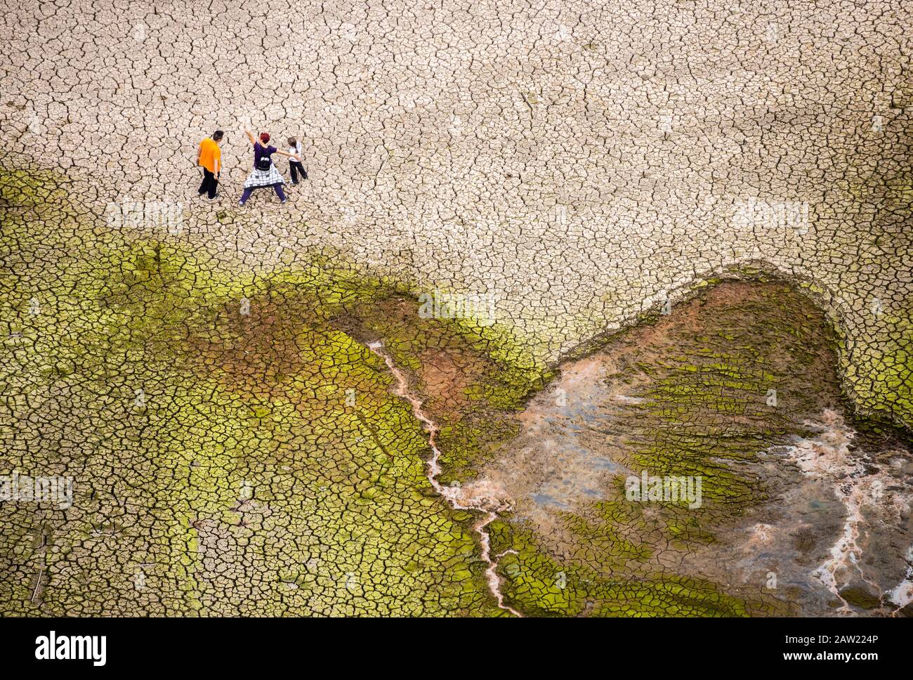 Blick von der Staumauer der Menschen, die auf gerissener Erde des leeren Reservoirs laufen Stockfoto