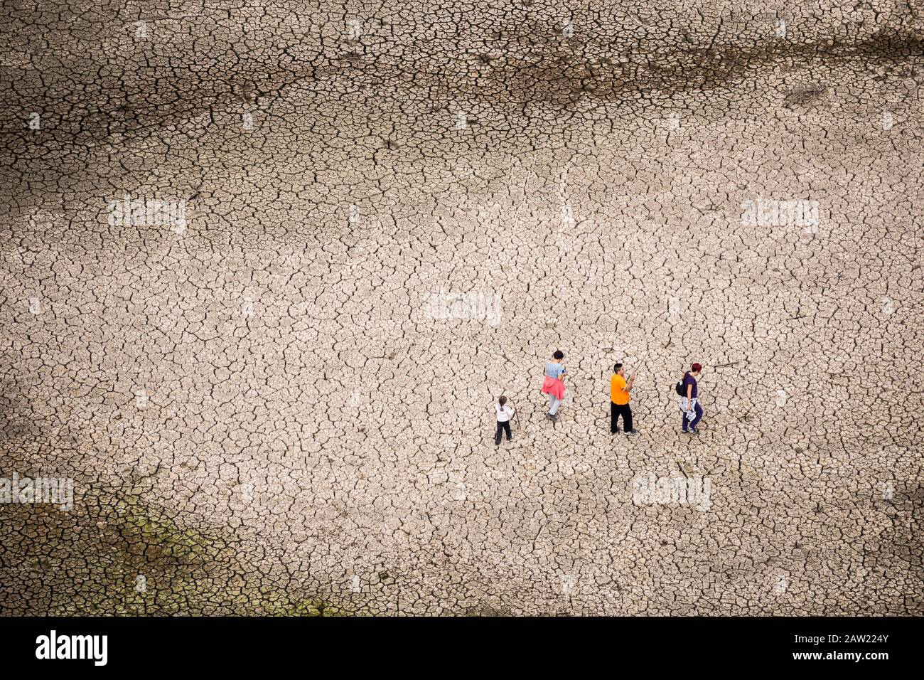 Blick von der Staumauer der Menschen, die auf gerissener Erde des leeren Reservoirs laufen Stockfoto