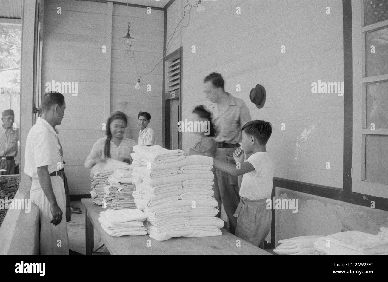 Personoeisches Oemoen und rotes Kruiswerk [Padang] Padang: Die indonesische Bevölkerung in den befreiten Gebieten wurde in einem schrecklichen Zustand gefunden. Hilfe in Form von Medikamenten und Lebensmitteln war sofort notwendig, aber es bestand auch ein dringender Bedarf an Kleidung. Textilvertrieb in der Nähe von Padang unter der Aufsicht von Dr. Koot vom 3-14 R.I. Datum: August 1947 Ort: Indonesien, Java, Niederländisch-Ostindien, Sumatra Stockfoto