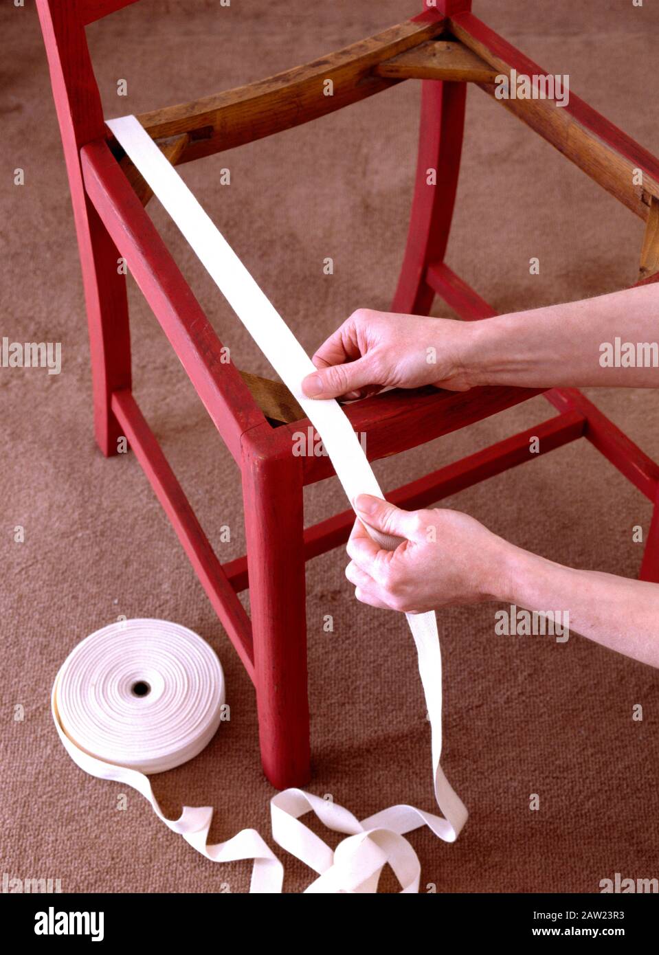 Nahaufnahmen der Hände das Gurtband auf einem rot lackierten Stuhl erneuern Stockfoto
