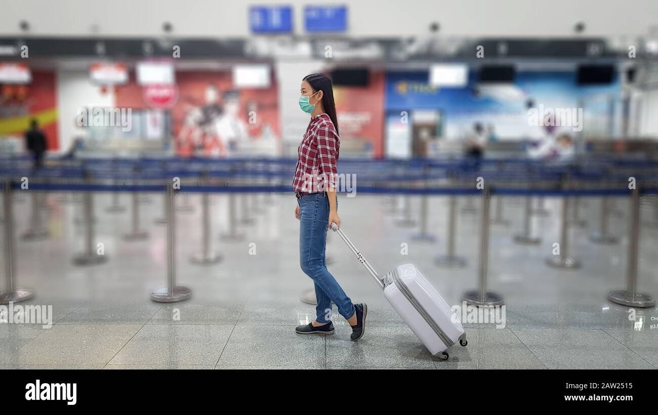 Asiatischer Tourist mit Gepäck, Tragemaske zur Verhinderung während der Reisezeit am Flughafenterminal zum Schutz vor der neuen Coronavirus 2019-Infektion Stockfoto