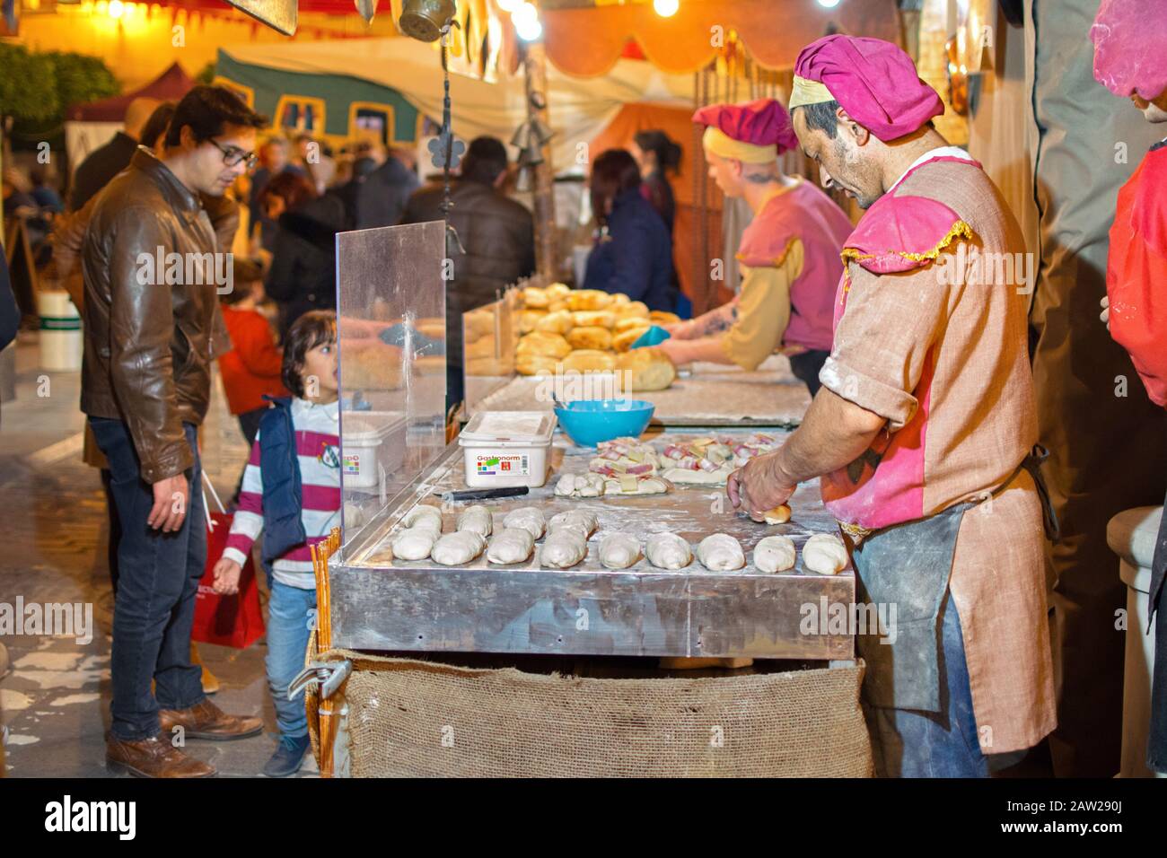 Orihuela, Spanien, 1. Februar 2020: Traditioneller Bäckermann, der dem Brot Gestalt gibt und es auf einem mittelalterlichen Markt in Spanien backt. Stockfoto