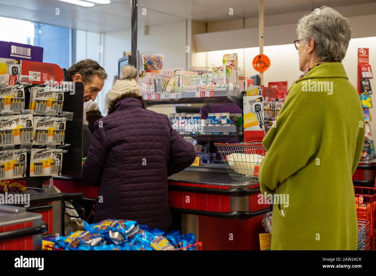 Käufer stehen an der Kasse eines Supermarktes Schlange und legen Produkte auf das Förderband Stockfoto