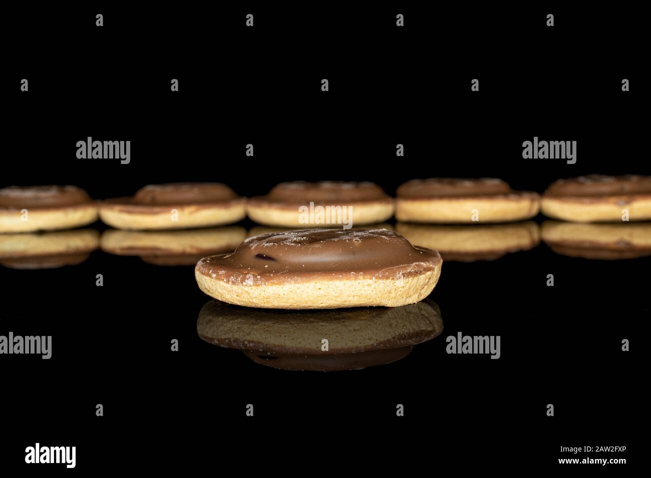 Die sechs vorderen Schokoladenkuchen konzentrieren sich isoliert auf schwarzes Glas Stockfoto