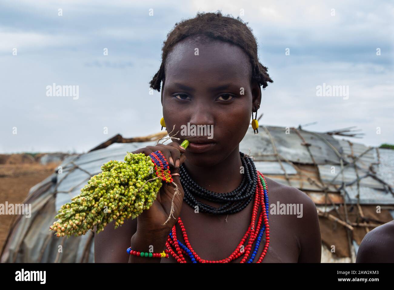 Omorate, Äthiopien - Nov 2018: Dasanech-Stammfrau kaut Sorghum vor dem Stammeshaus. Omo-Tal Stockfoto