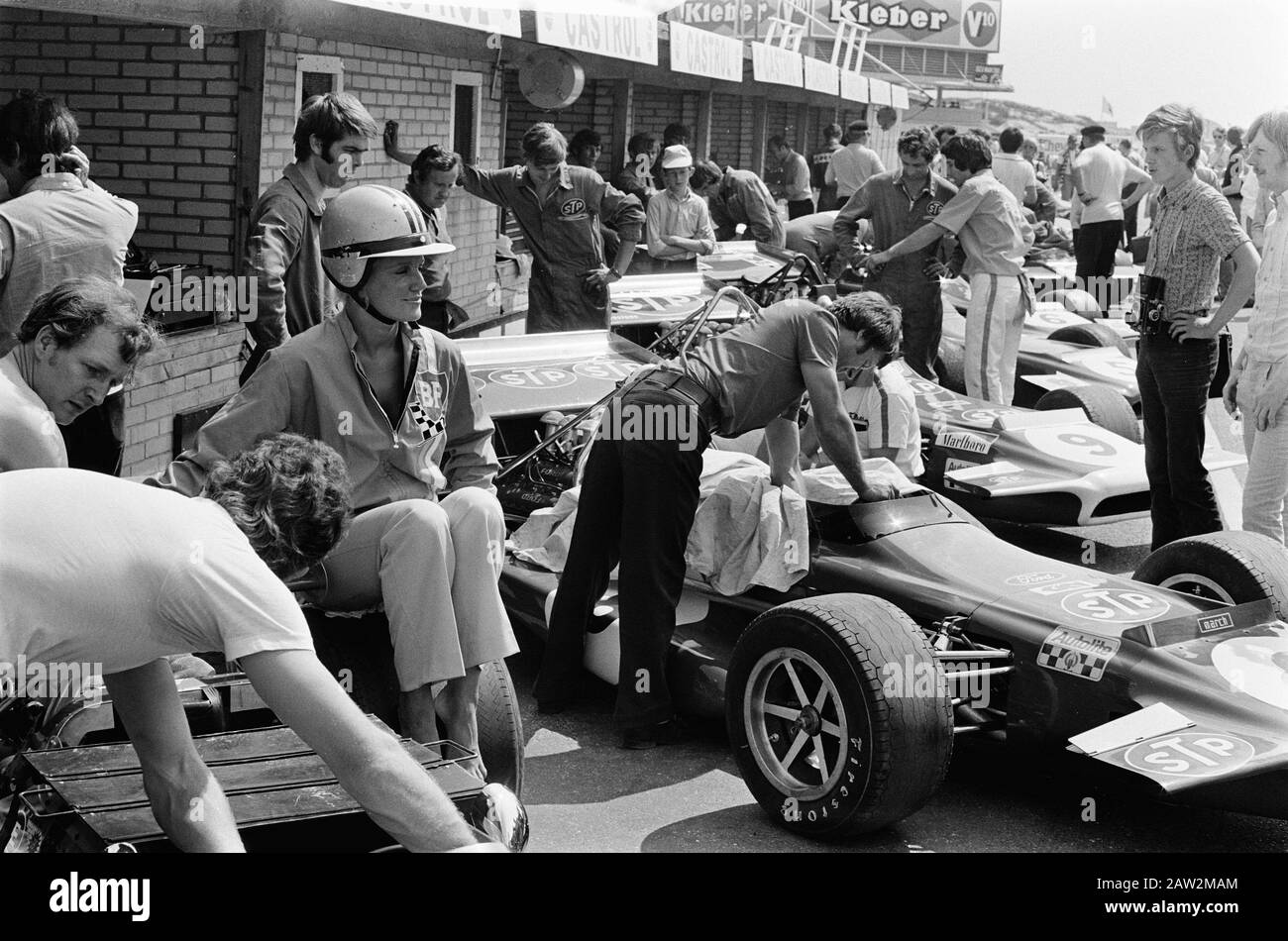 Nederlands: Grand Prix 1970 voor Formule i wagens te Zandvoort; eerste trainingsdag. Beim großen Preis von Holland 1970 wird eine Reihe von vier Fahrzeugen vom Typ March 701 in den Boxengruben eingesetzt. Der Kamera am nächsten ist Chris Amons STP-gesponserter Werkswagen (#8), wobei Jo Sifferts ähnlicher Wagen (#9) hinter sich durch seine weiß-lippige Kühleröffnung auszeichnete. Dahinter stehen die beiden Autos des Tyrrell Racing Teams (Note Elf Sponsoring): Jackie Stewarts Wagen ist #5; François Ceverts Wagen ist #6. Der Mitbegründer von March Alan Rees ist der kürzere der beiden Männer, die das linke Hinterrad von Amons Auto inspizieren. Stockfoto