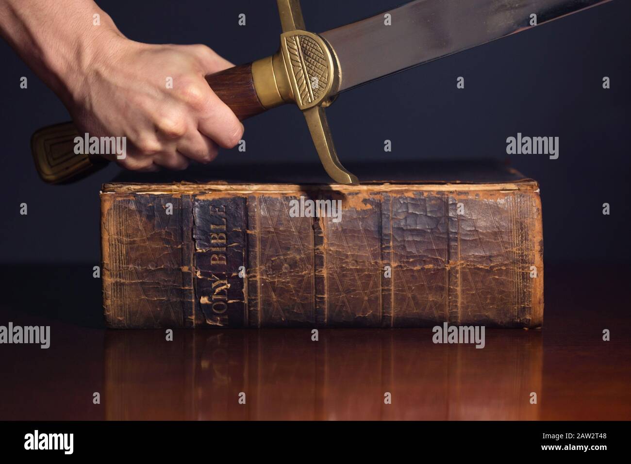 Starke männliche Hand mit Schwert und Bibel Stockfoto