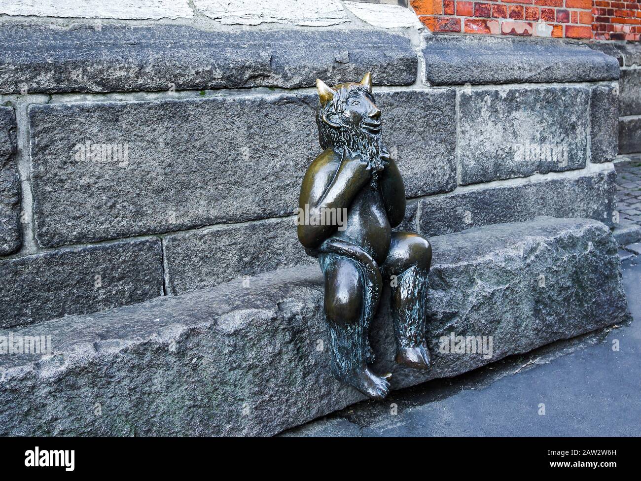 Der niedliche kleine Teufel sitzt auf einem Stein vor der Marienkirche (St. Marienkirche), Lübeck. Stockfoto