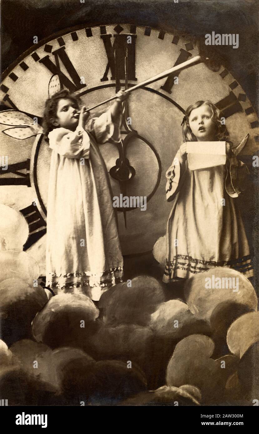 1905, DEUTSCHLAND: Zwei kleine Mädchen wie Engel verkünden das Glückliche Neujahr. Foto von unbenziftem deutschen Fotografen für Postkarten, die von produziert wurden Stockfoto