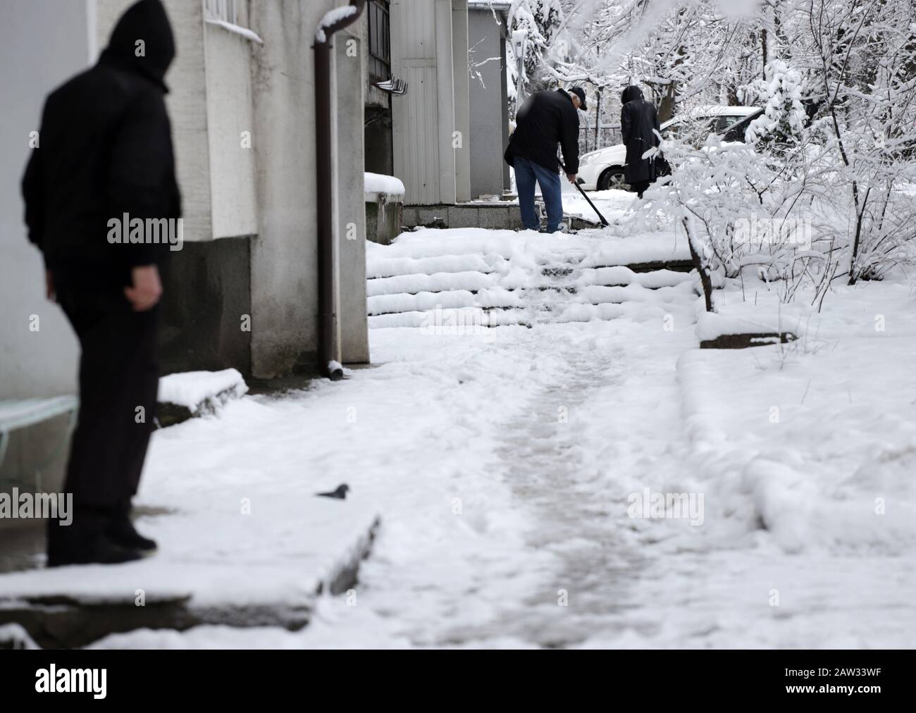 Die Leute gehen auf einem unverputzten Gehweg, auf einem glatten und eisigen Gehweg. Stockfoto