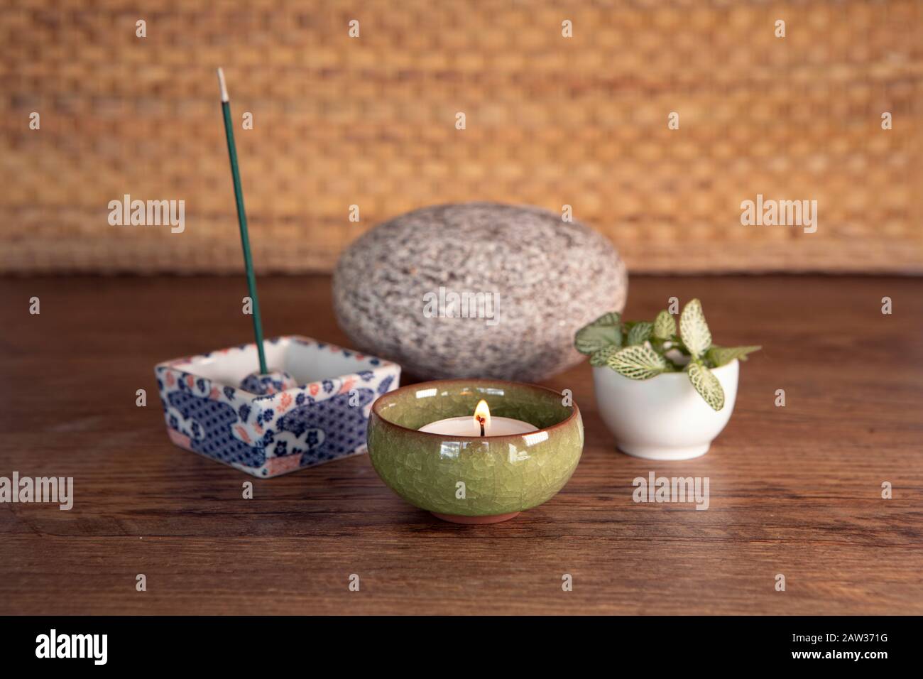 Dekoration mit brennendem Weihrauch, Kerze, Stein und frischer Pflanze. Yoga, Meditationsausrüstung. Stockfoto