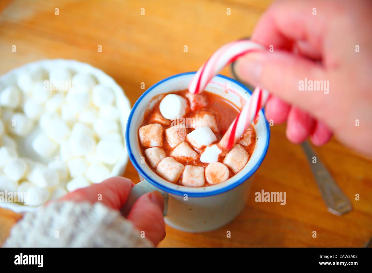Eine Frau mit einer Tasse heißen Kakao, Marshmallows und eine Zuckerstange Stockfoto