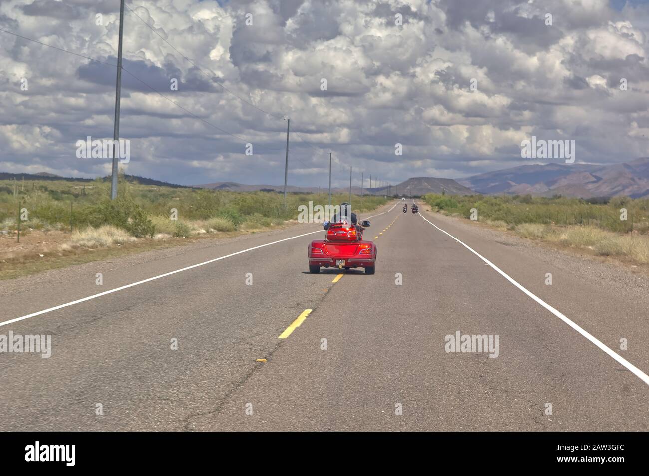 Ein Motorradfahrer auf einem 3-Rad-Rad, der die Mittellinie auf einer abgelegenen 2-spurigen Straße in der Nähe von New River Arizona entlang stredet. Dies wurde meinem Fahrzeug entnommen, während ich w Stockfoto