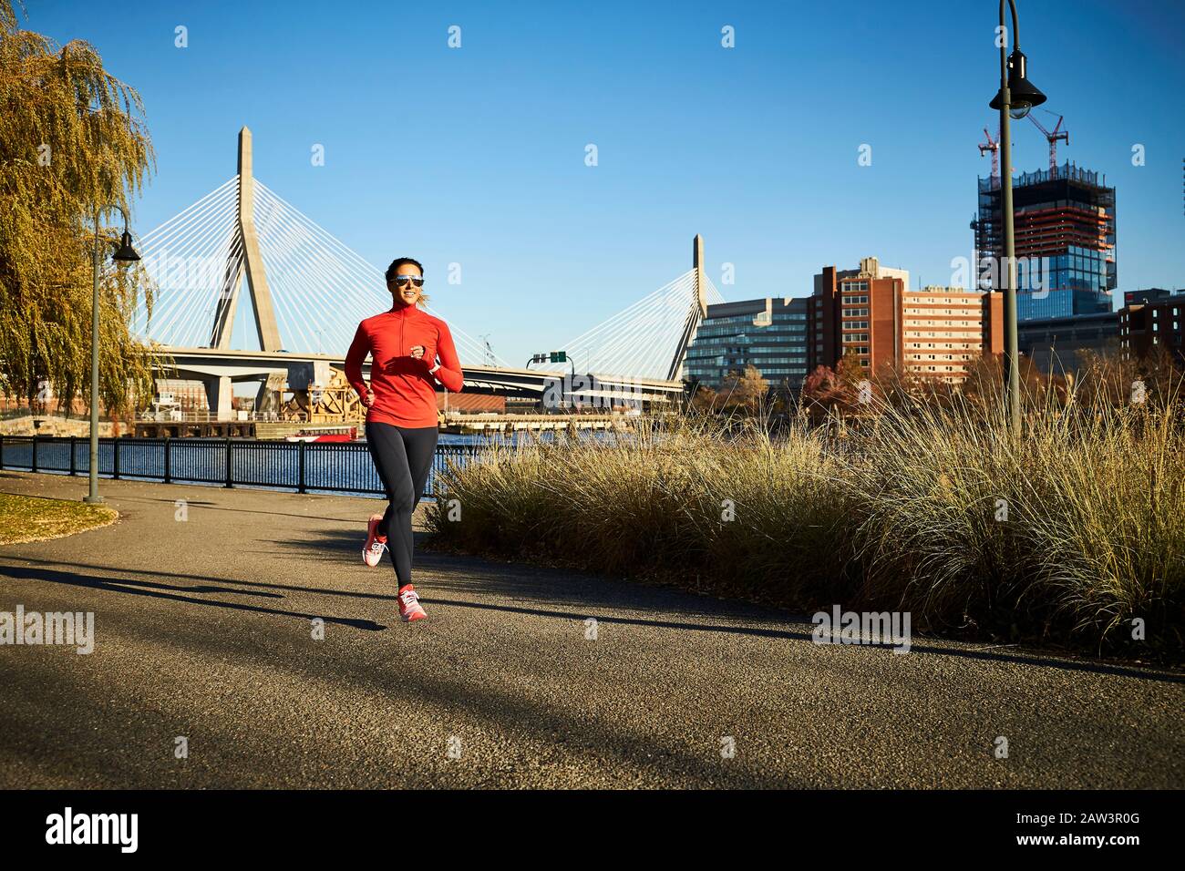 Eine Frau, die vor der Zakim Bridge in Boston läuft. Stockfoto