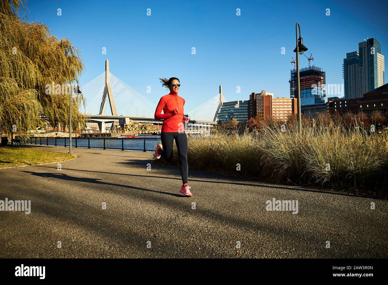 Eine Frau, die vor der Zakim Bridge in Boston läuft. Stockfoto