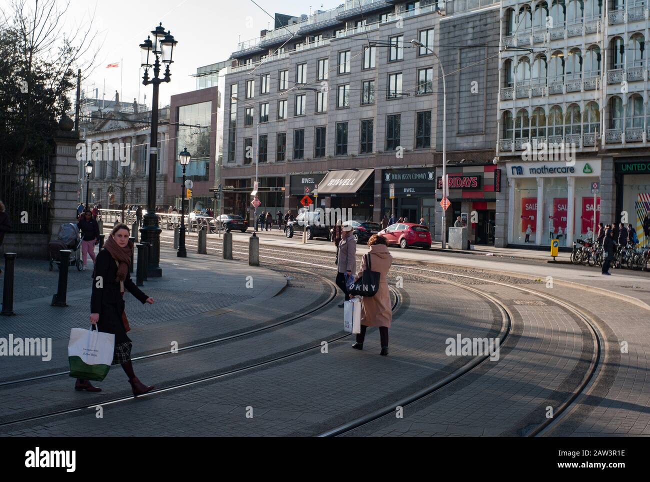 Dublin, Irland - 29. Januar 2020: Fußgänger, die LUAS-Straßenbahngleise auf St Stephens Green im Stadtzentrum von Dublin kreuzen Stockfoto