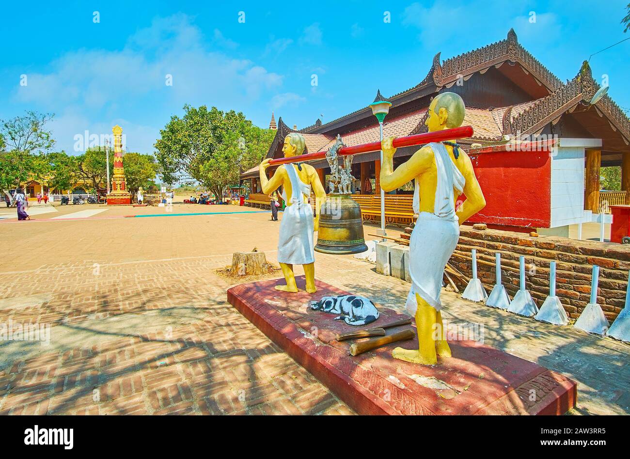Bagan, MYANMAR - 25. FEBRUAR 2018: Gelände der Pyi Pagode ALO-daw mit geschnitztem Holzpavillon und ritueller Glocke, die von zwei Monchstatuen auf dem Vorgruppe gehalten wird Stockfoto