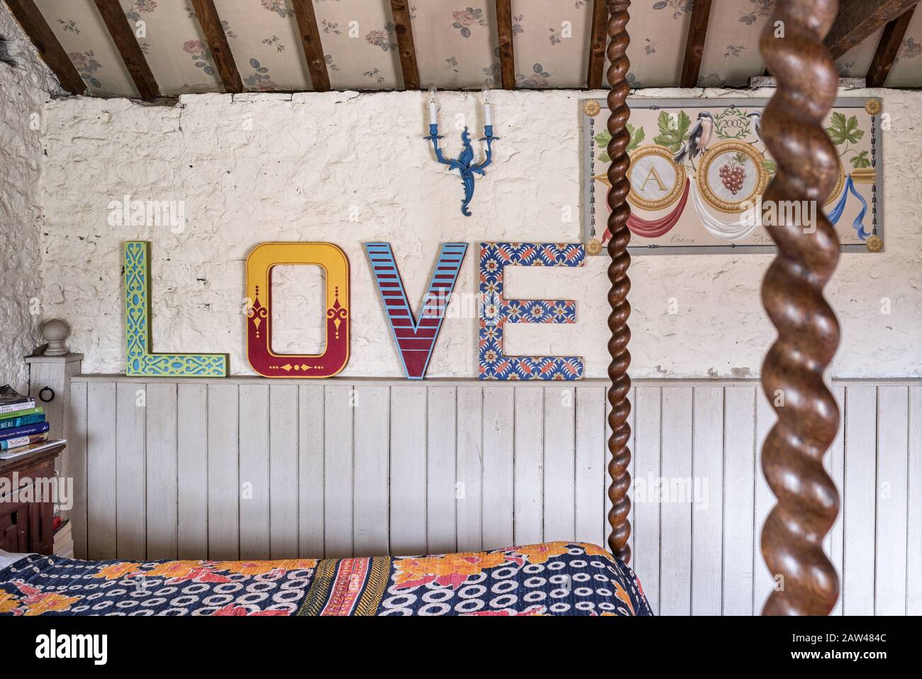 Farbenfrohes "Love"-Zeichen im rustikalen Schlafzimmer Stockfoto