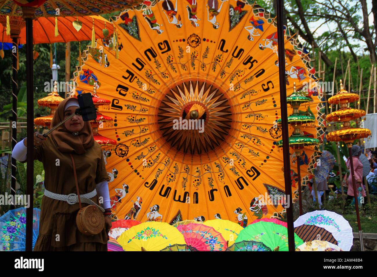 Die Besucher fotografieren mit dem Smartphone in einer Reihe von Sonnenschirmen, die auf dem Nusantara Umbrella Festival im Prambanan-Tempel Yogyakarta, Sonntag, 8. September 2019, ausgestellt sind. Dieses jährliche Dachfestival zeigt Tausende von Schirmkreationen aus ganz Indonesien. Der Prambanan-Tempel wurde ausgewählt, weil er historischen Wert enthält und von der UNESCO als Kulturerhaltung Indonesiens anerkannt wurde. Stockfoto