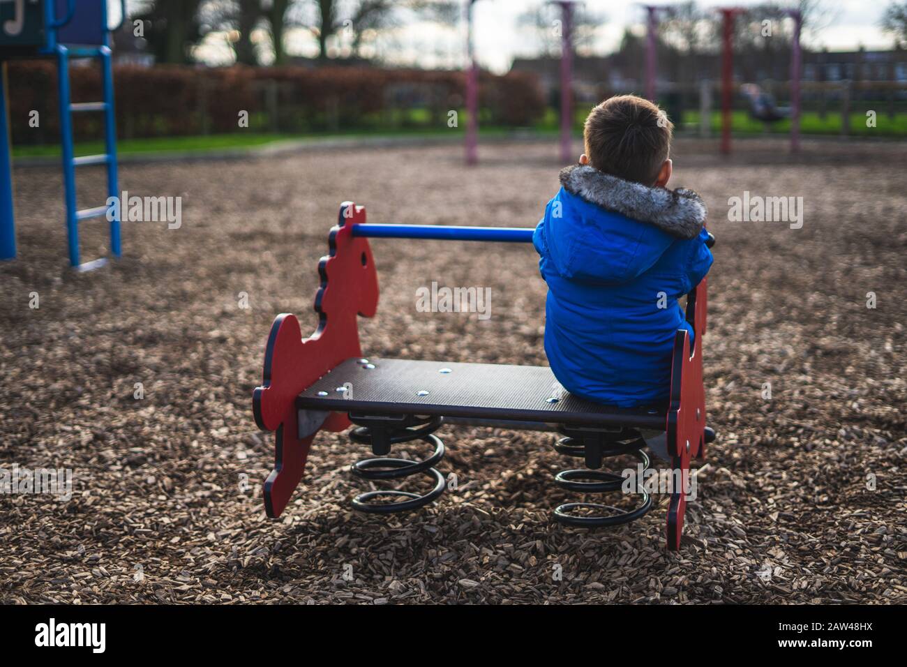 Die Rückseite eines kleinen Jungen, der allein in einem spielt parken Stockfoto