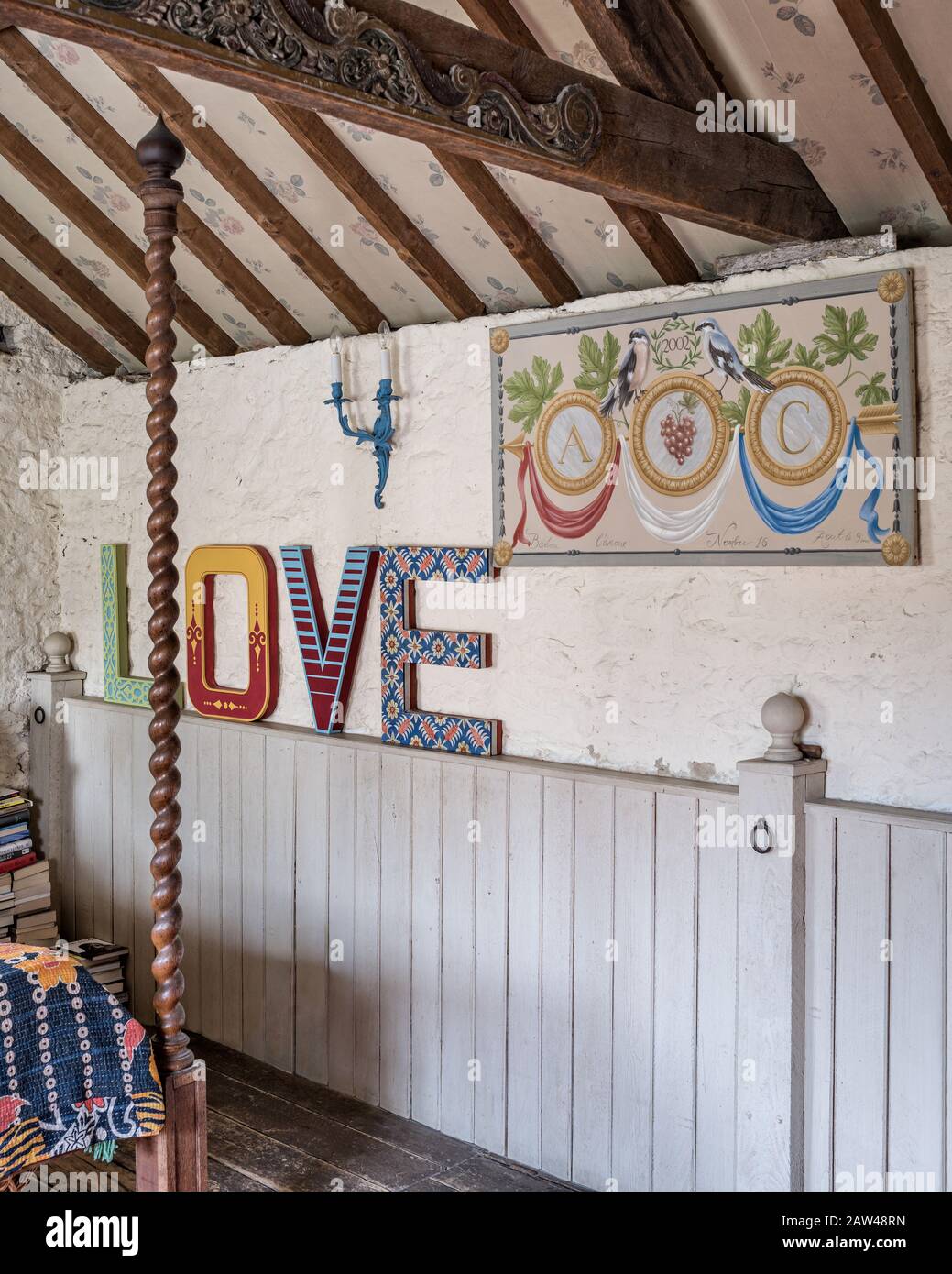 Farbenfrohes "Love"-Zeichen im rustikalen Schlafzimmer Stockfoto