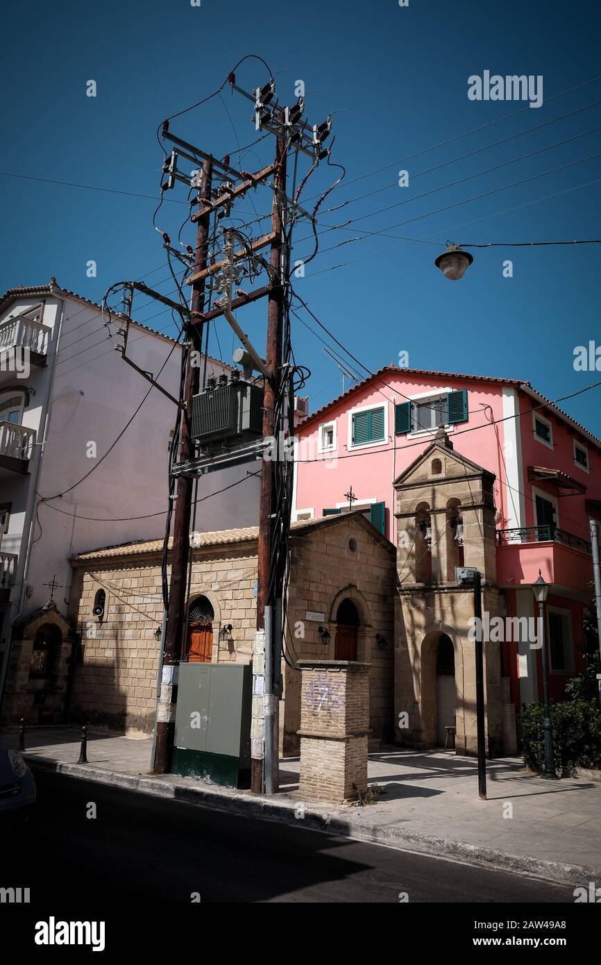 Eine kleine Kirche im Zentrum von zakynthos, die in einer Seitenstraße versteckt ist, liegt zwischen einer großen elektrischen Umspannstation und einem Gebäude. Stockfoto