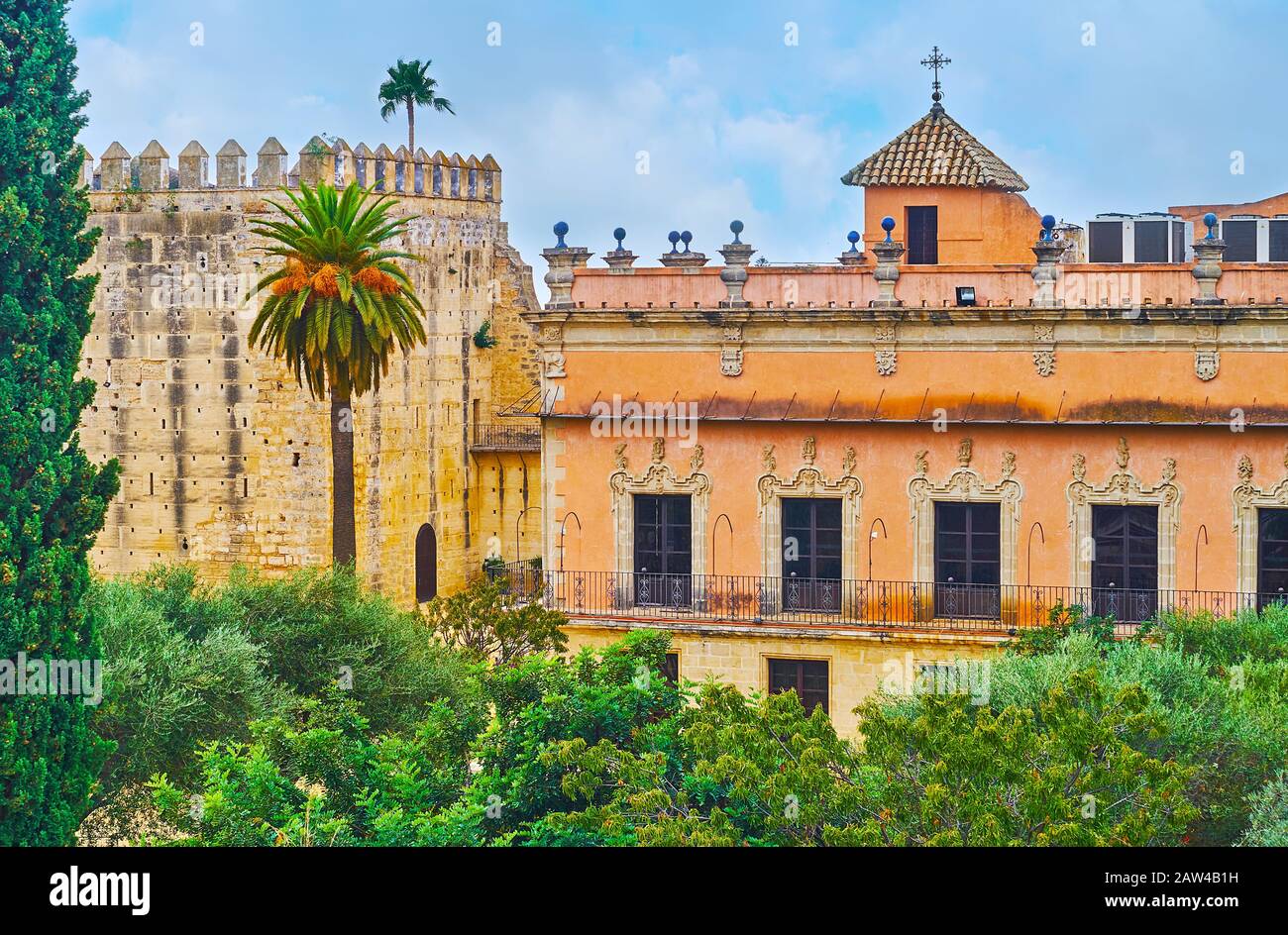 Der Blick auf den steinernen Turm Und den ockerfarbenen Palast von Villavicencio durch das üppige Grün des Alcazar-Gartens, Jerez, Spanien Stockfoto