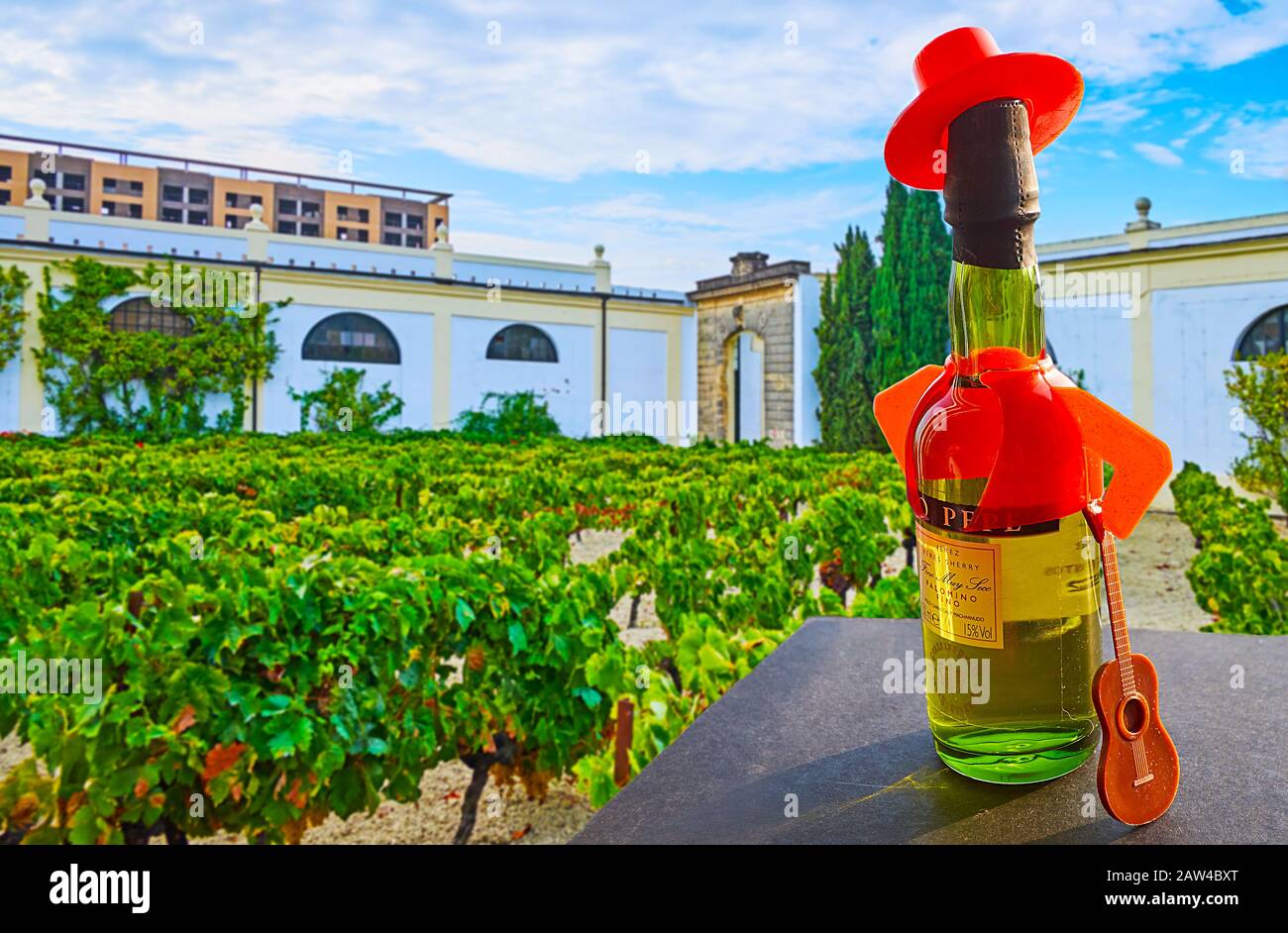 Jerez, SPANIEN - 20. SEPTEMBER 2019: Die Flasche Sherrywein in Hut, Jacke und Haltegitarre (Tio Pepe Logo) vor Weinberg, in Bodega Stockfoto