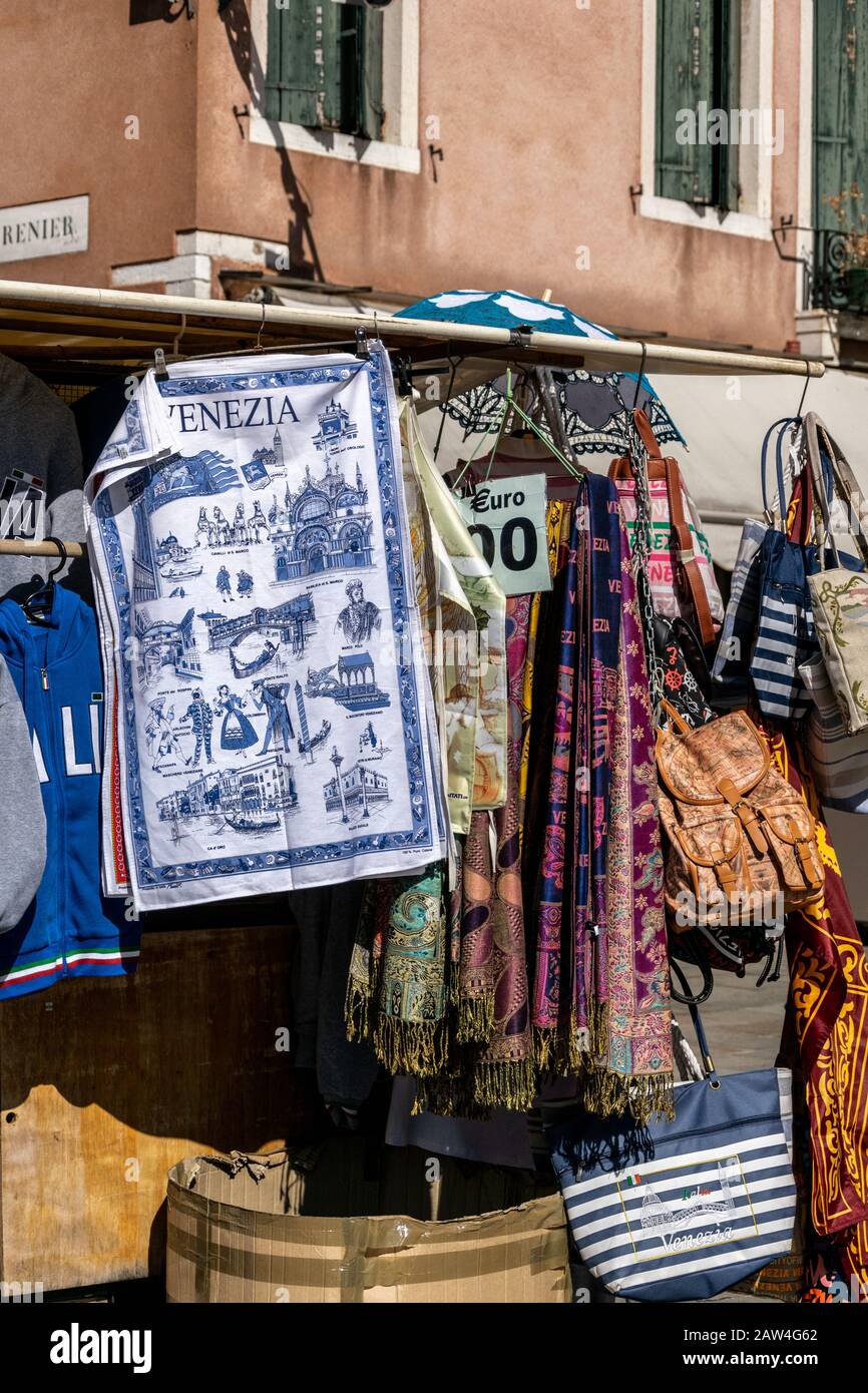 Ein Marktstall, an dem Touristen Souvenirs verkauft werden, einschließlich eines Geschirrhandtuchs mit Bildern von Wahrzeichen, Venedig, Italien Stockfoto