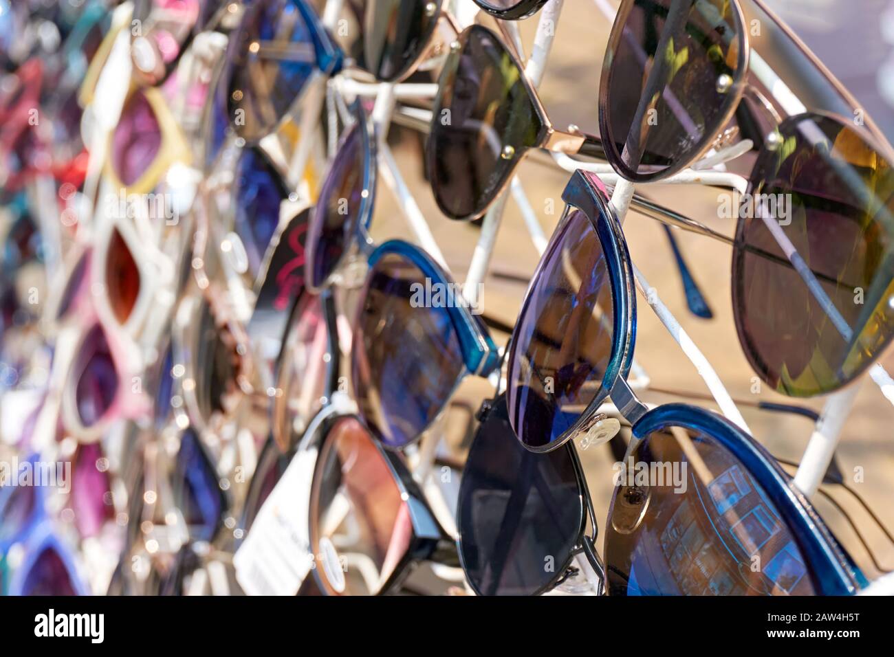 Nahaufnahme einer bunten Sonnenbrille mit dunklen Gläsern auf einem weißen Schauständer im Sommer. Bild mit selektivem Fokus. Stockfoto