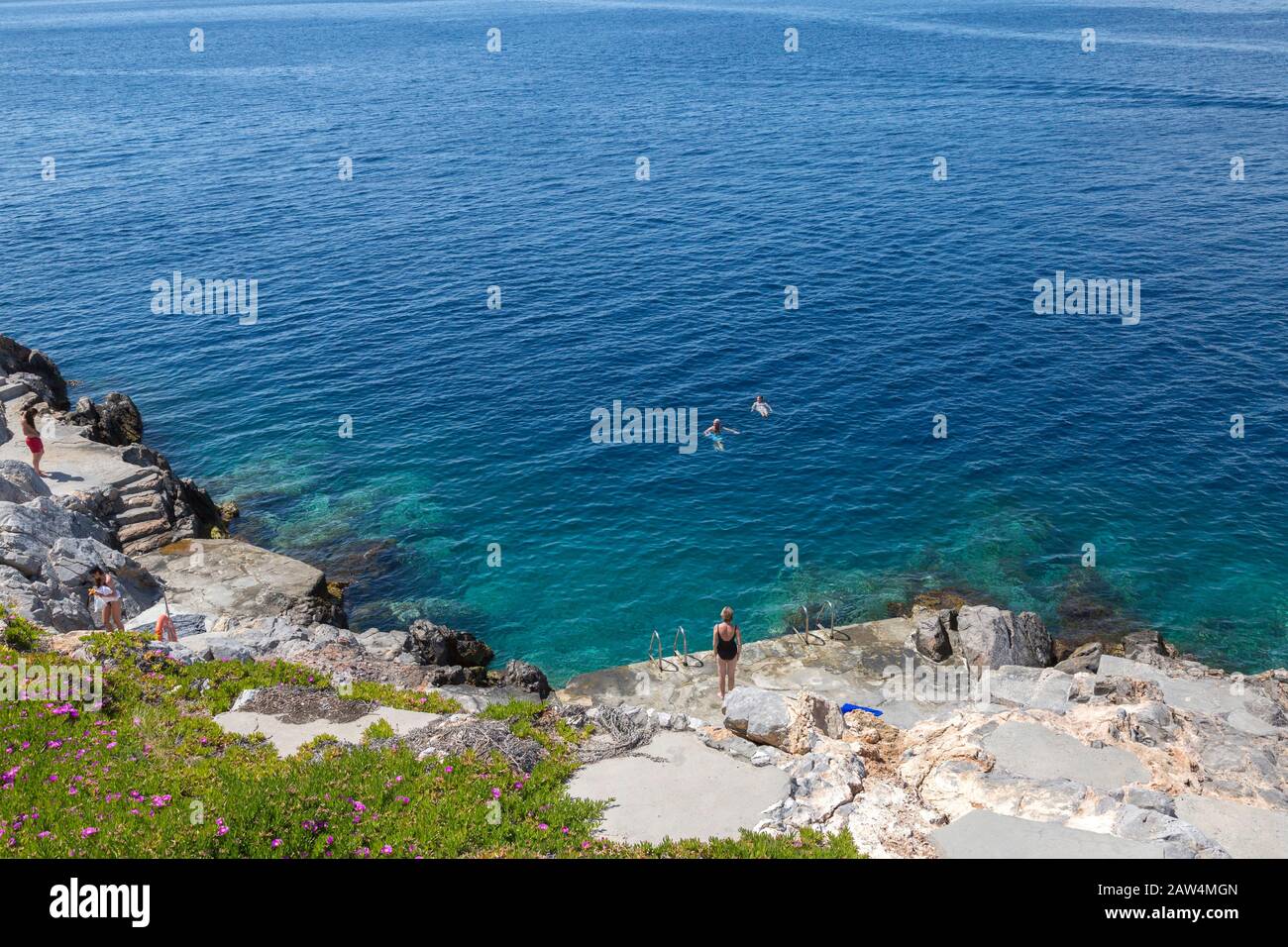 Stoney Strand von Hydra Island in Griechenland, mit Sonnenbädern. Küste der ägeischen See an einem sonnigen Tag im Frühling. Stockfoto