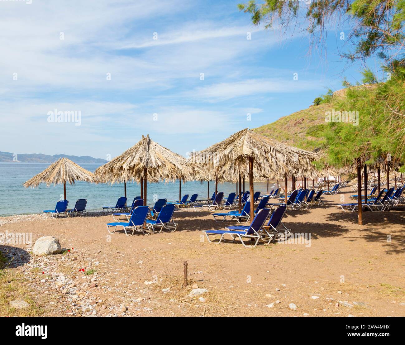 Vlichos Strandszene auf Hydra Island, Griechenland mit Liegestühlen und Palapas. Stockfoto