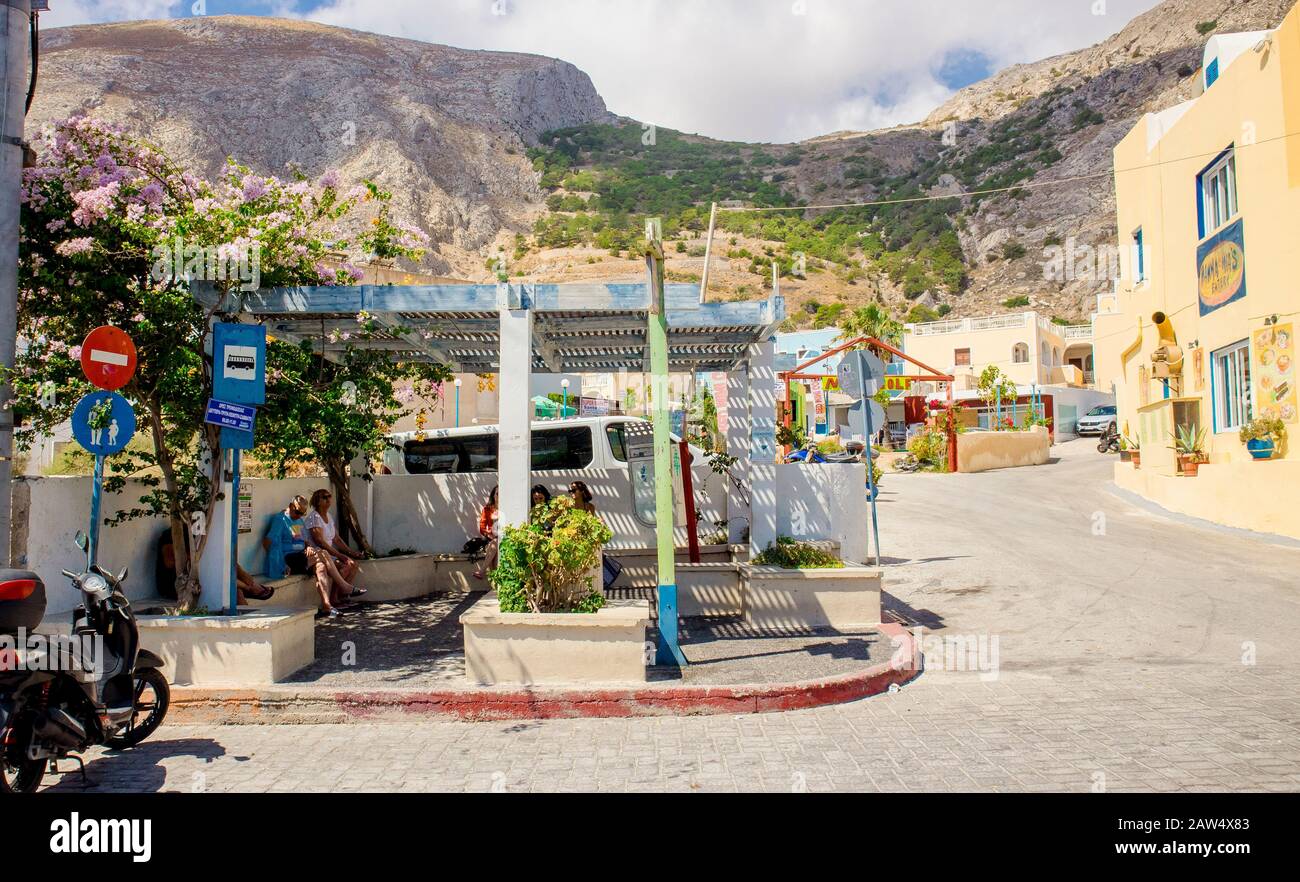 Kamari, Santorini/Griechenland-14Jul2019: Kamari Strandbustop. Touristen sitzen und warten auf den Bus. Berg Mesa vouno im Hintergrund. Stockfoto