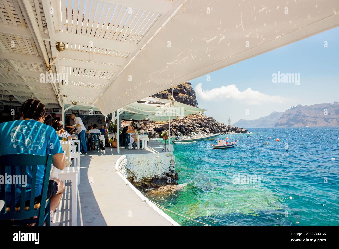 Oia, Santorini/Griechenland 14Jul2019-Ammoudy Bay mit Fischerbooten und Fischtavernen. Touristen verbringen Zeit und essen in traditionellen griechischen Tavernen. Stockfoto