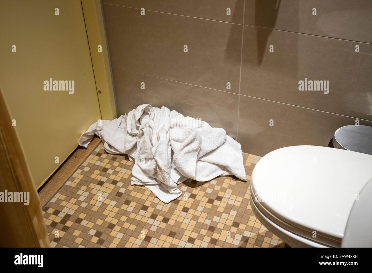 Haufen schmutziger gebrauchter Handtücher auf dem Boden des Hotelbades. Ordnung und Sauberkeit ersetzen Sie nur die gebrauchten Handtücher auf dem Boden durch saubere. Wasser, Seife und Energie sparen Stockfoto