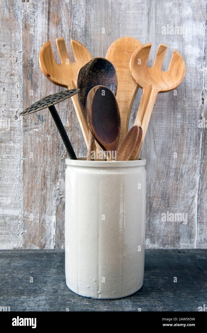 Umweltfreundliche Küchengeräte, einschließlich Holzlöffel in Vintage-Töpfercontainer auf Holzgrund Stockfoto