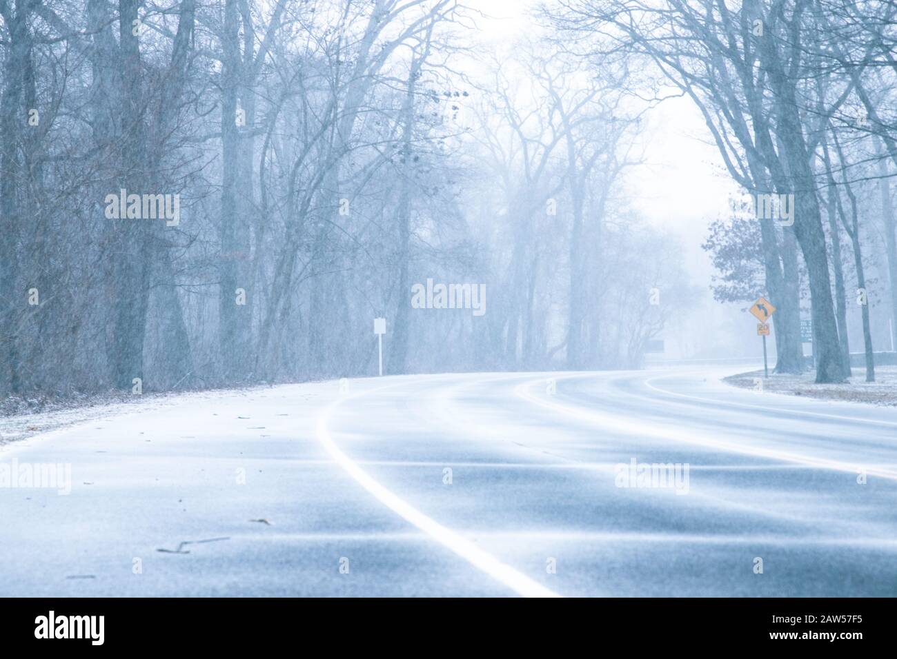 Weiß-draußen-Wetterbedingungen, wenn an einem Wintertag Schnee auf der Straße durch Wälder fällt Stockfoto