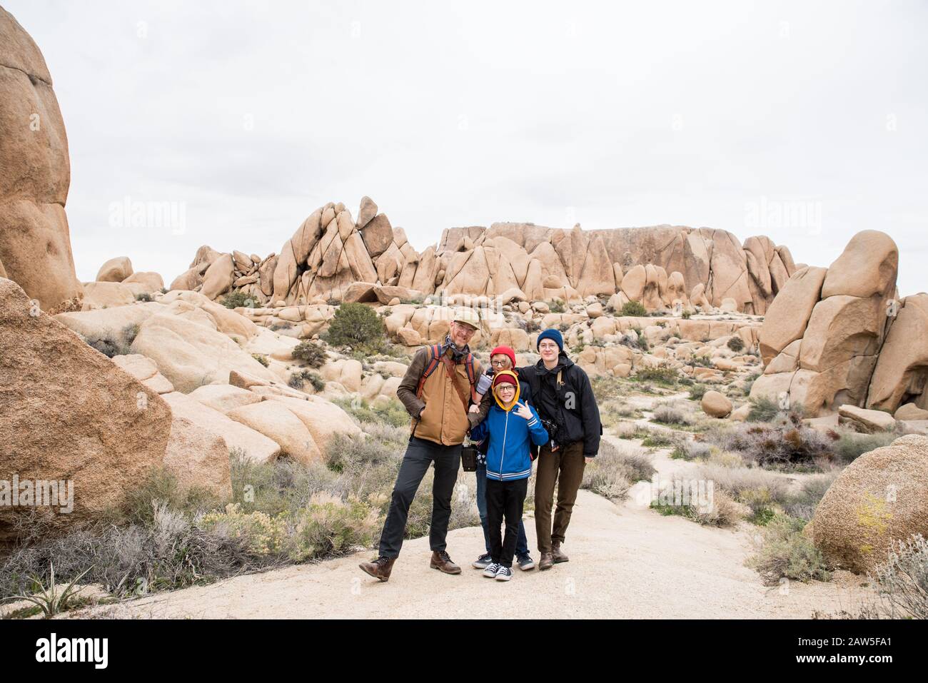 Vierköpfige Familie, die Spaß in der Wüste hat, umgeben von Felsen und Sträuchern Stockfoto