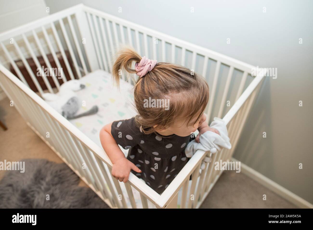 Hoher Winkel der blonden Kleinkind Mädchen in Krippe Bett. Stockfoto