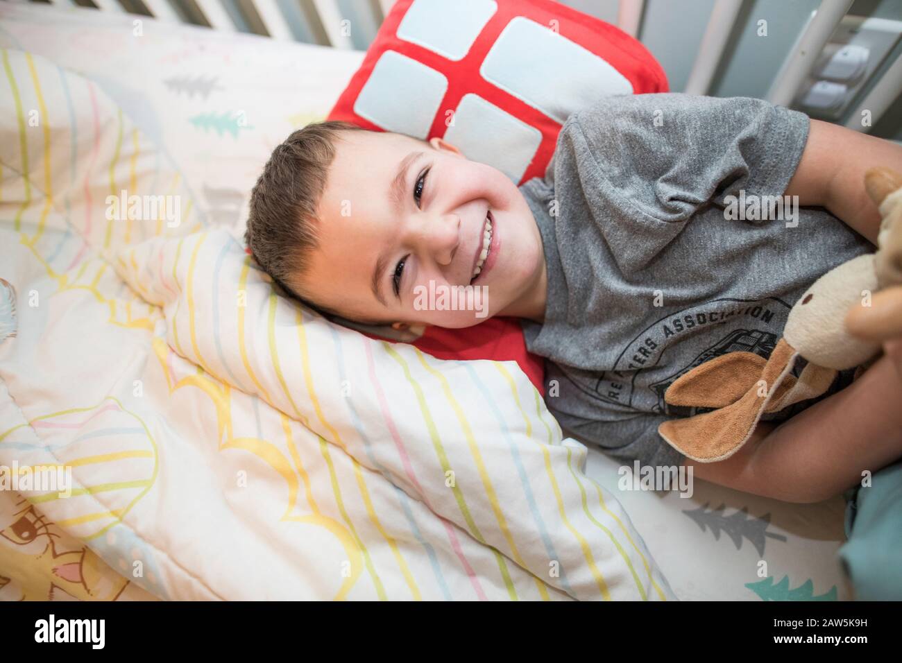 Glücklicher Kleinkind Junge ruht sich auf dem Kissen im Bett. Stockfoto