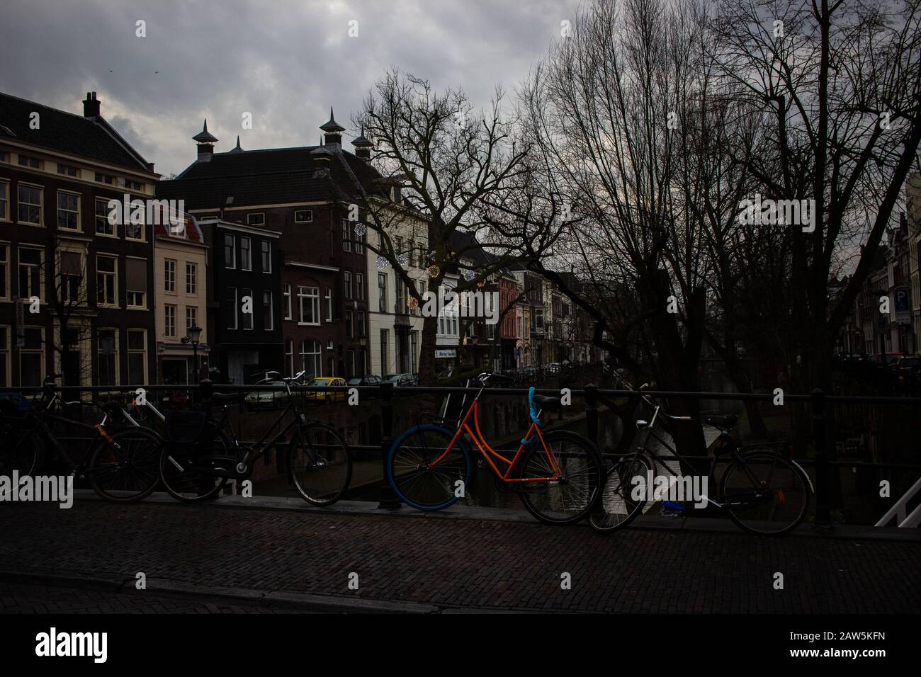 Oudegracht, UTRECHTER - 26/1/2020 - EIN Blick auf Fahrräder, die im Hintergrund an den Geländern mit Eckhäusern und Geschäften befestigt sind Stockfoto