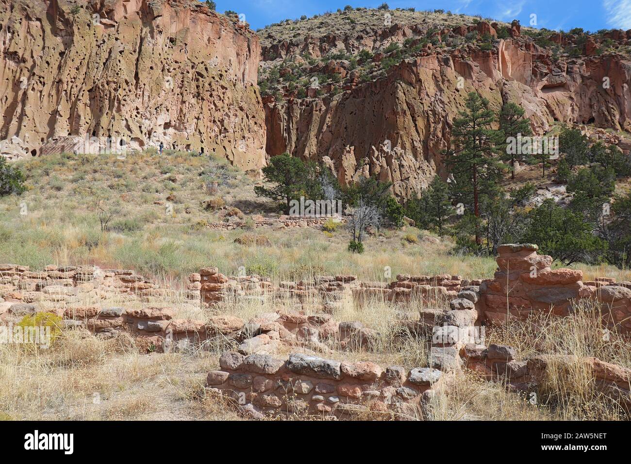 Teil der Tyuonyi-Ruinen der angestammten Pueblo-Völker mit einem rekonstruierten Pueblo an den Klippen entlang des Hauptschleifenweges im Frijoles Canyon bei Ba Stockfoto
