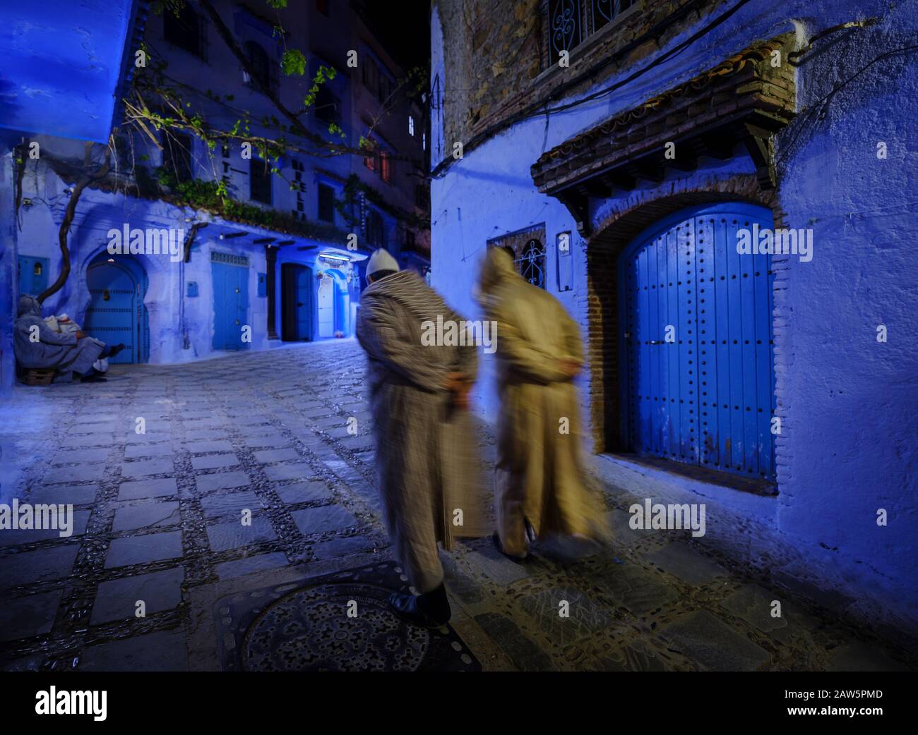 Chefchaouen, MAROKKO - CIRCA MAI 2018: Zwei Personen, die nachts in der Hauptstraße von Chefchaouen spazieren. Stockfoto