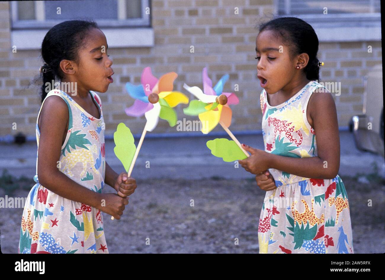 Austin Texas USA, um 1993: Acht Jahre alte schwarze Zwillingsschwestern blasen auf Nadelräder, um sie zum Drehen zu bringen.©Bob Daemmrich Stockfoto