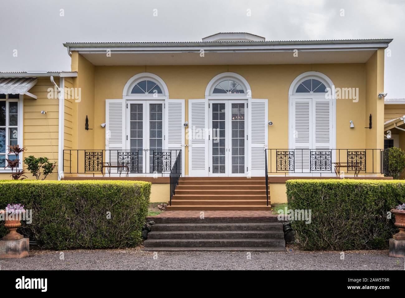 Waimea, Hawaii, USA. - 15. Januar 2020: Hauptniederlassung der Parker Ranch. Gelbe Wände mit weißen Fensterrahmen und Fensterläden des Flügels des Haupthauses. Grüne he Stockfoto