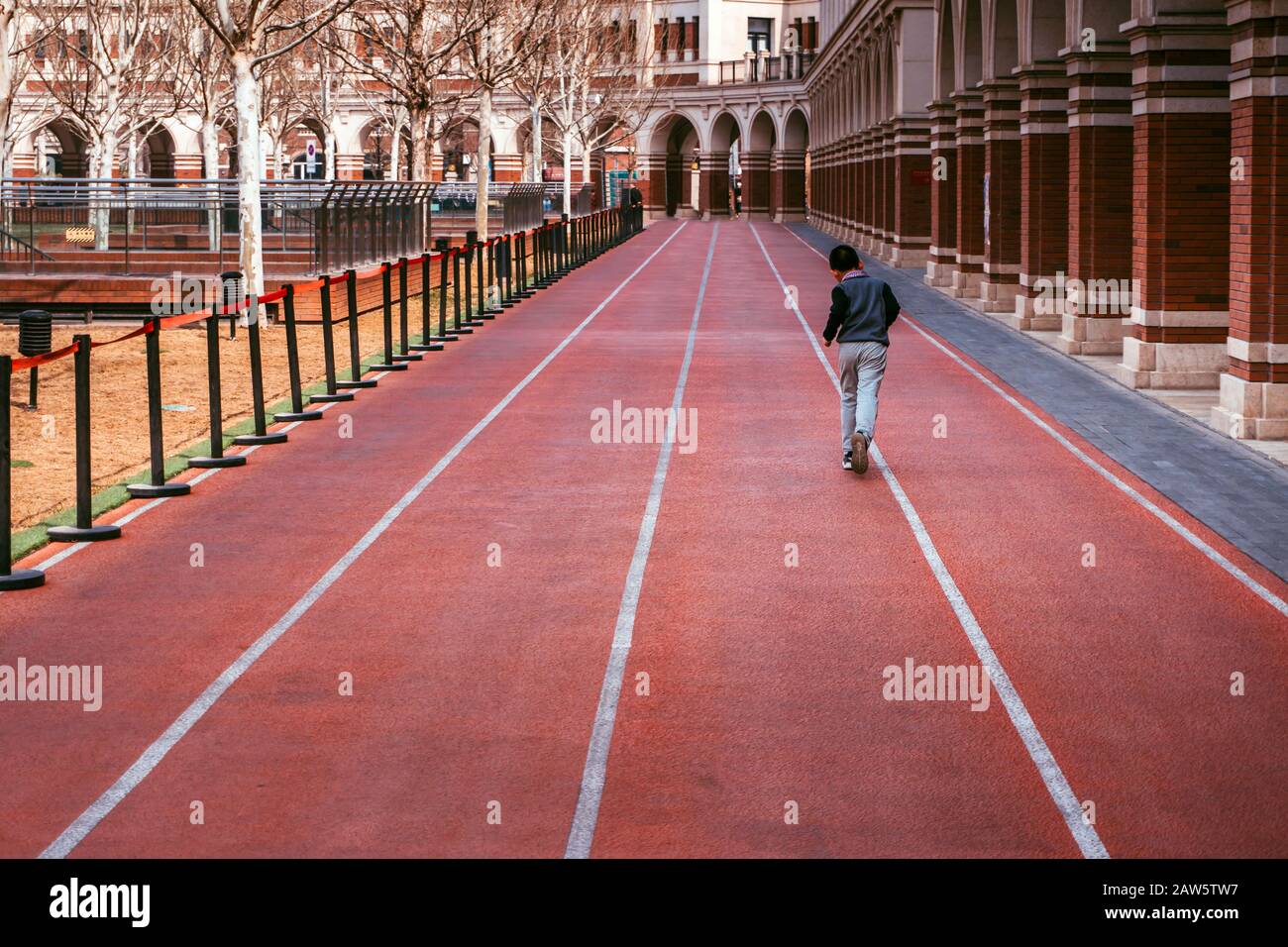 Der Junge läuft auf einem roten Joggingpfad Stockfoto