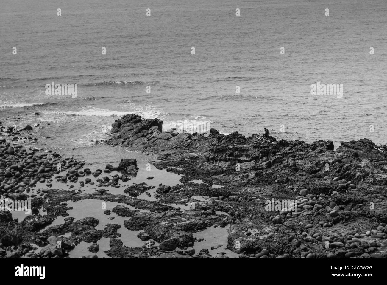 Fischer sitzt auf den Felsen. Sehr dramatische Schwarzweiß-Szene. Stockfoto